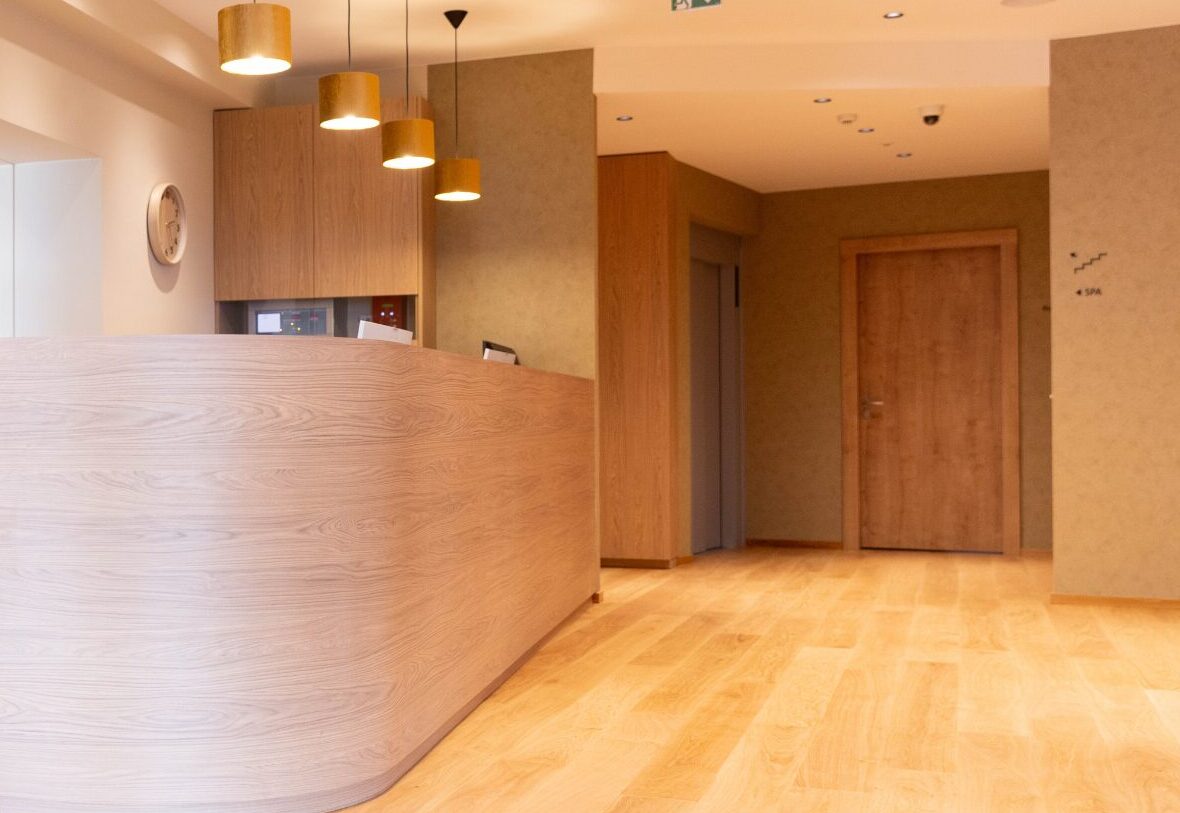 Réception d’un hôtel rénové par l’agence, comptoir courbe en bois clair (photo : VieW architecture & décoration)
