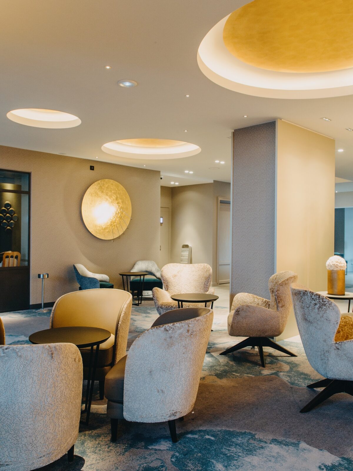 Salon de restaurant rénové par l’agence, fauteuils en velours clair et oculus dorés au plafond (photo : VieW architecture & décoration)